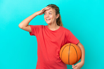 Little caucasian girl playing basketball isolated on blue background smiling a lot