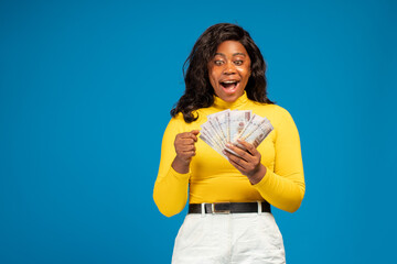 surprised looking african woman holding some money