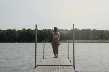 Unrecognizable woman on her back on a dock in front of a lake, concept freedom