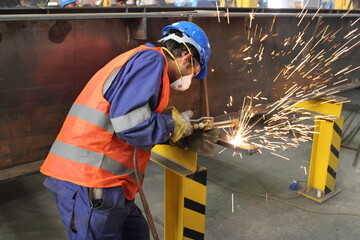 Fototapeta premium Skillful metal worker working with arc welding machine in factory while wearing safety equipment. Metalwork manufacturing and construction maintenance service by manual skill labor concept.
