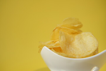 Potato chips.Chipsy. chips close-up in ceramic cup on bright yellow background. Fast food and snack. High quality photo