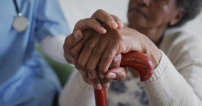 Close up of american african female doctor and senior patient holding hands