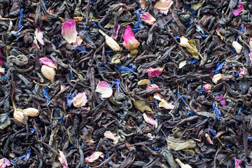 Mix tea with dried fruits and dried flowers. Tea background. Black tea with pink and blue petals. Health.