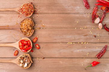 Chili with various seasonings on wooden floor top view with copy space