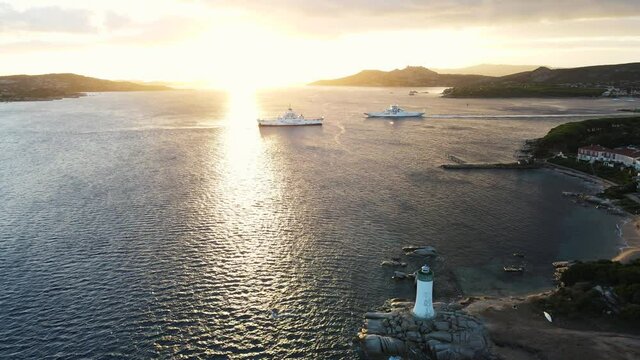 dramatic sunrise, two ferrys cross the stretch to the island of la maddalena in the mediterranean sea. the lightower is blinking. Drone aerial shot, Sardinia Italy.