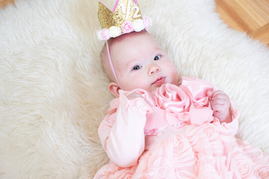 6-month-old baby girl. Half birthday. Happy birthday, princess. Cute caucasian baby girl in a pink dress. Tiara baby