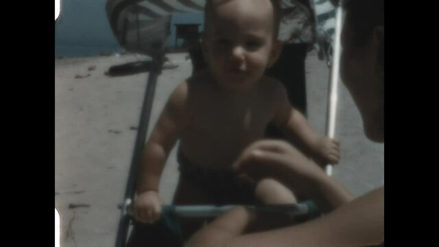 Happy Beach Baby 1952 - A smiling baby nearly jumps out of the stroller at the beach. 