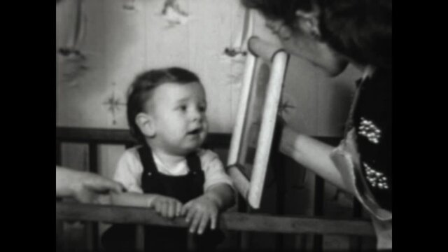Baby Kisses GI Dads Picture 1952 - A baby in the crib kisses a portrait of his father dressed in uniform. 