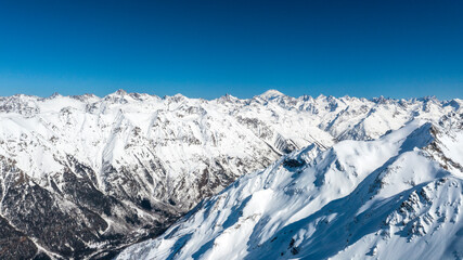 Caucasus Mountains, Panoramic view of the ski slope with the mountains Belalakaya, Sofrudzhu and Sulakhat on the horizon in winter day. Dombai ski resort, Western Caucasus, Karachai-Cherkess, Russia.