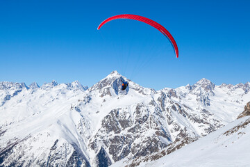 Paragliding in the mountains, People paragliding tandem above mountain in winter in Dombay ski...