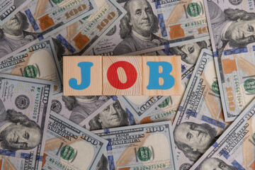 The word JOB composed of colored letters on a background of 100 American dollar bills