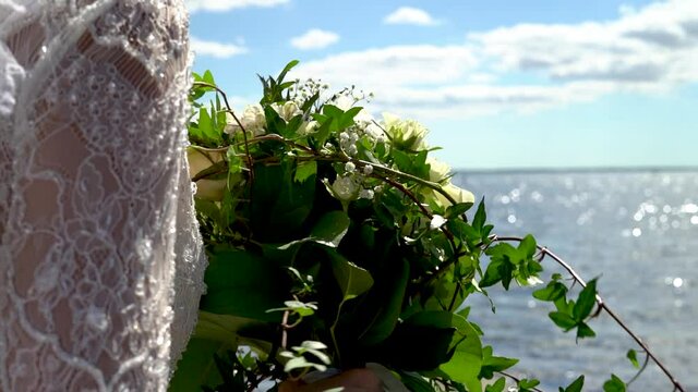 Brudbukett h&aring;ller i handen g&aring;endes vid stranden