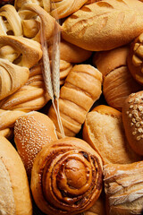 Close up of different types of breads and golden buns with ears of wheat. Food and bakery concept....