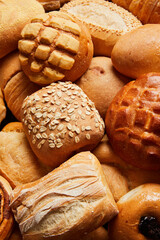 Close up of different types of breads and golden buns. Food and bakery concept. Salty and sweet food background. Bakery and carbohydrates. Vertical photo.