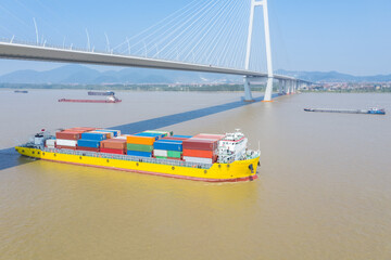 container ship sailing on inland river under cable-stayed bridge