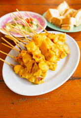Closed up street food it's grill pork satay or grilled pork on white dish served with bean sauce and pickle cucumbers and onions in vinegar.