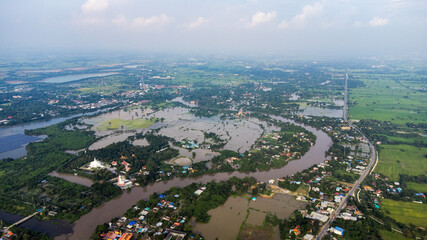 Fototapeta premium Flood waters overtake a house and rice field at Central of Thailand in 2021. Many buildings are submerged in water. Photo disaster from above view by drone