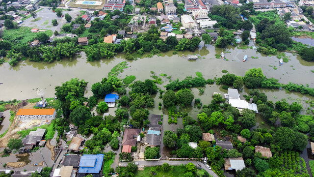Flood waters overtake a house and rice field at Central of Thailand in 2021. Many buildings are submerged in water. Photo disaster from above view by drone