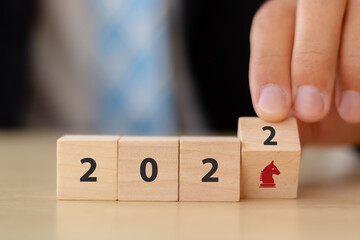 Business strategy and game plan in 2022 concept. Businessman hand flips wooden cubes 