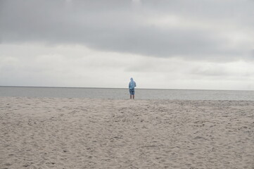 Solitary Male Figure Looking out to Sea on Wet Sandy Beach in Daylight