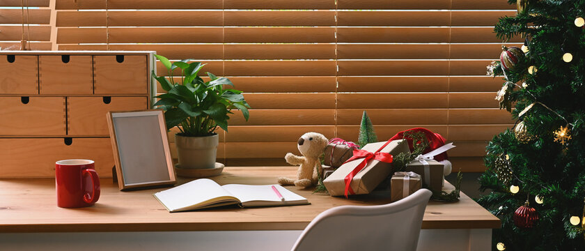 Christmas presents, coffee cup and notebook on wooden table in living room.