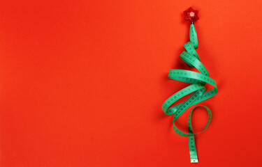 Christmas tree made of measuring tape on a red background with copy space