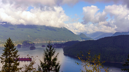 Naklejka premium Spectacular, scenic view from Burnaby Mountain Park down pristine Burrard Inlet with cloud-capped North Shore mountains to Indian Arm with oil tanker just in view.