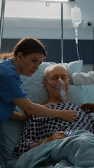Patient with breathing problems fainting in hospital ward bed at modern equipment medical facility....