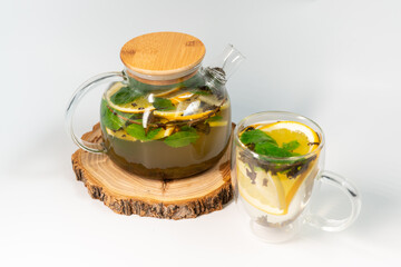 Ginger-orange in a transparent teapot on a white background next to a filled transparent mug