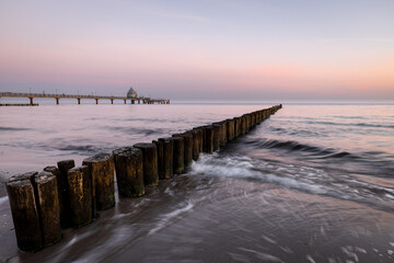 sunrise at the coast of baltic sea with pier and icoming waves at the groins, Zingst,, Western-Pomerania, Germany
