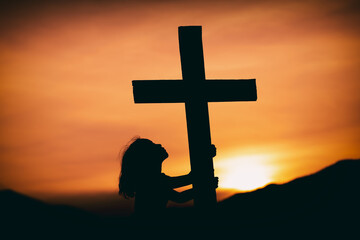 young girl looking at the cross with hope in god at sunset, christian silhouette concept.