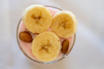 top view of a dairy dessert with banana, almond in a glass.