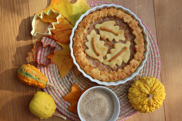 Traditional homemade Apple Pie with fall decoration on a wooden table with ornamental pumpkins and fallen leaves