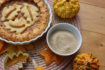 Traditional homemade Apple Pie with fall decoration on a wooden table with ornamental pumpkins and fallen leaves