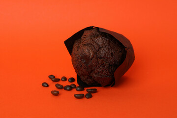 Naklejka premium Chocolate muffin with coffee seeds on orange background
