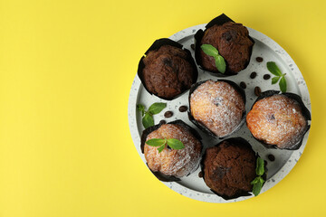 Tray with chocolate muffins on yellow background