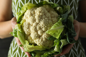Woman in apron holds fresh cauliflower, close up