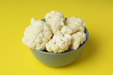 Fresh juicy cauliflower slices in bowl on yellow background