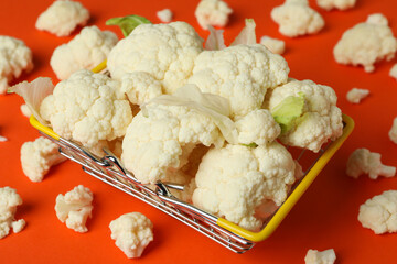 Slices of fresh juicy cauliflower in basket on orange background