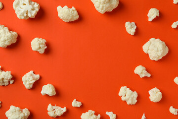 Flat lay composition with slices of cauliflower on orange background