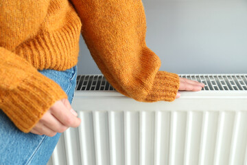 Concept of heating season with girl sitting on radiator - obrazy, fototapety, plakaty