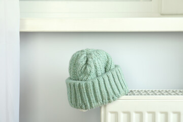 Concept of heating season with knitted hat on radiator