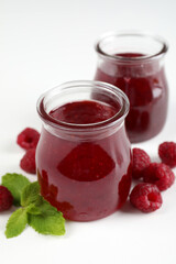 Jars of raspberry jam with ingredients on  white background