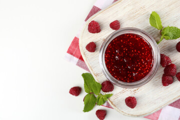 Jar of raspberry jam with ingredients on white wooden stand