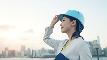ヘルメットをかぶって都市を眺める女性　設計士　建築家