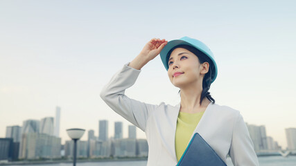 ヘルメットをかぶって都市を眺める女性　設計士　建築家