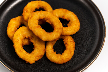 onion rings on a black plate on a white background close up