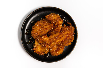 Chicken bytes in Tokyo sauce on a black plate on a white background top view 