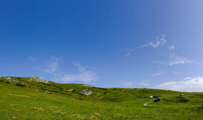 gorgeous green nature landscape with alpine huts and blue sky panorama
