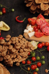 Fototapeta na wymiar Food photography, plating of cherry tomatoes, mushrooms, peppers and sliced ​​cheese, placed on rustic wooden table